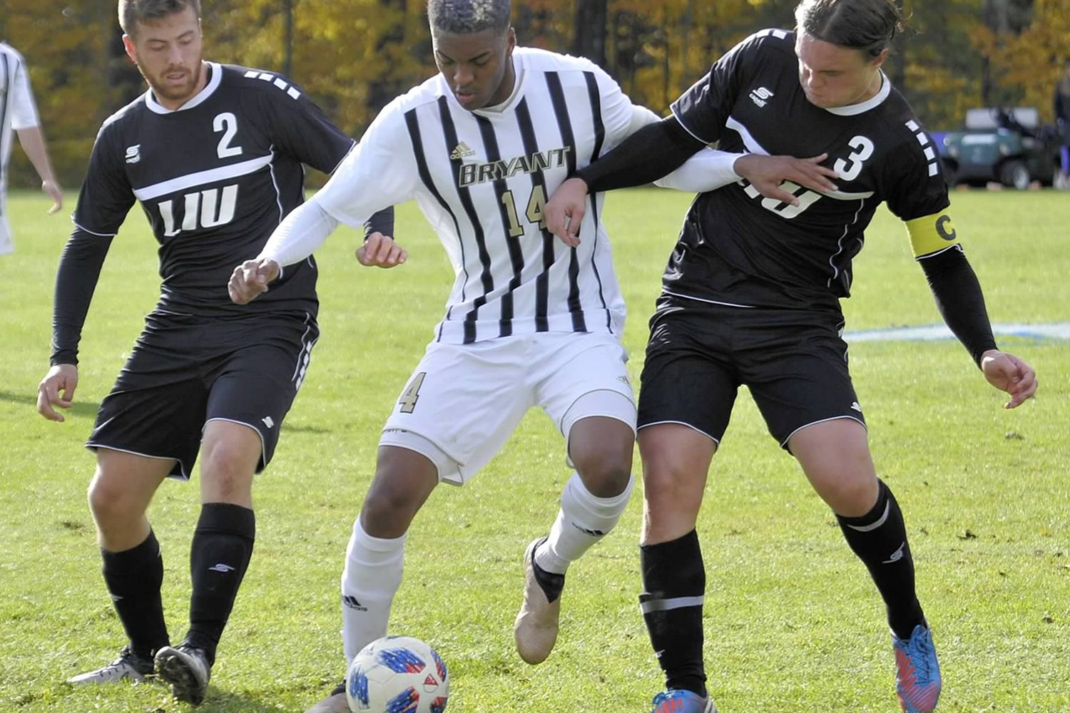Tony shielding the ball between two LIU defenders